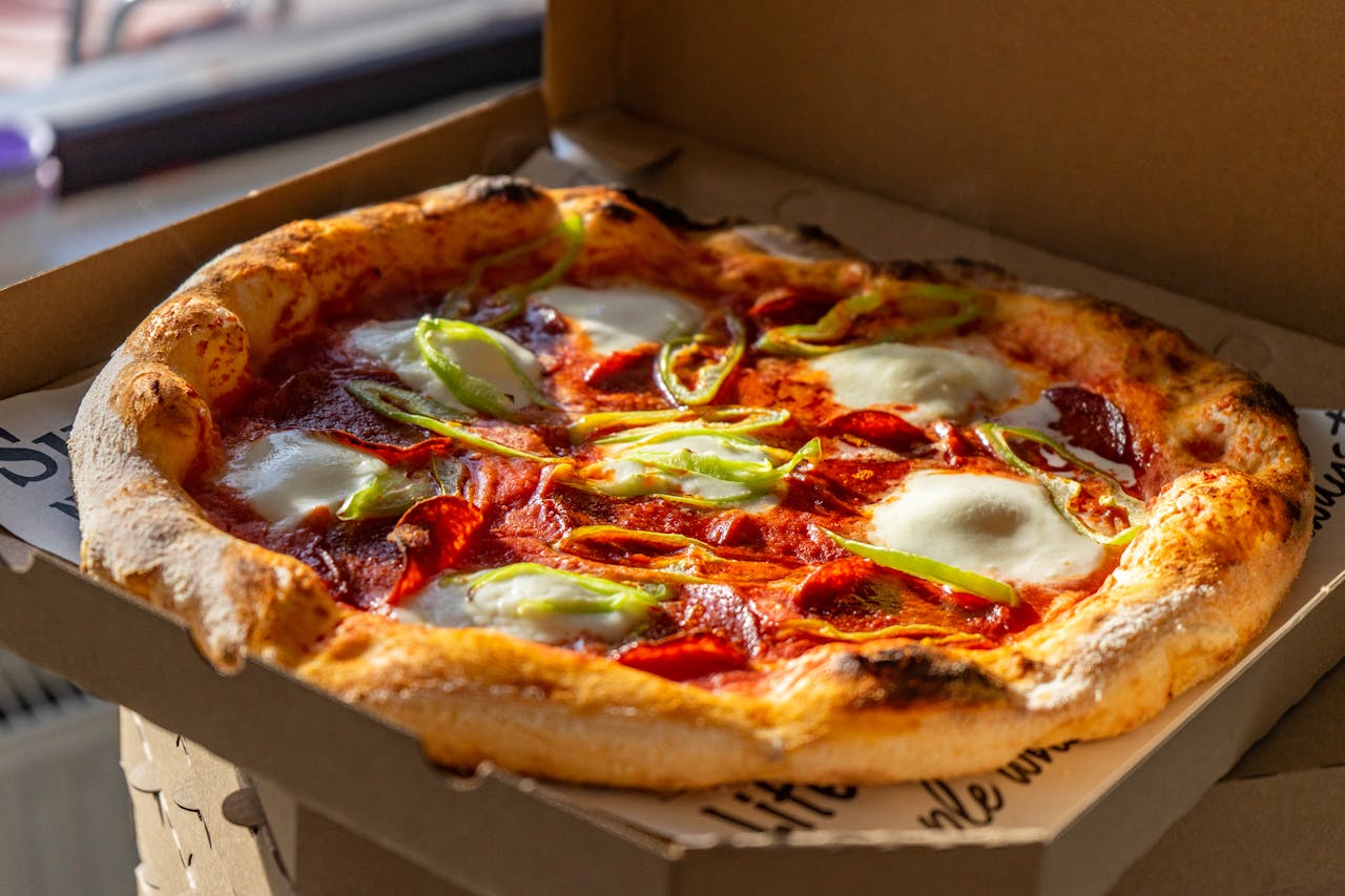Tasty Neapolitan pizza with fresh ingredients in a cardboard box, perfect for takeout.