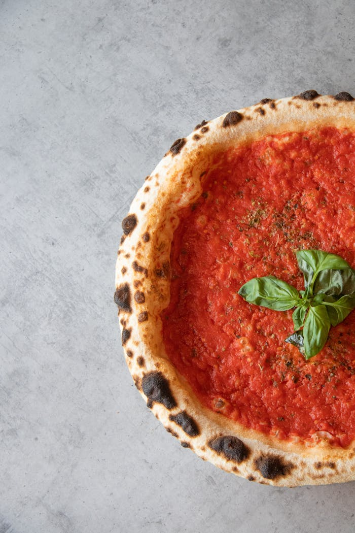 Freshly baked Margherita pizza with basil and tomato sauce, top view.