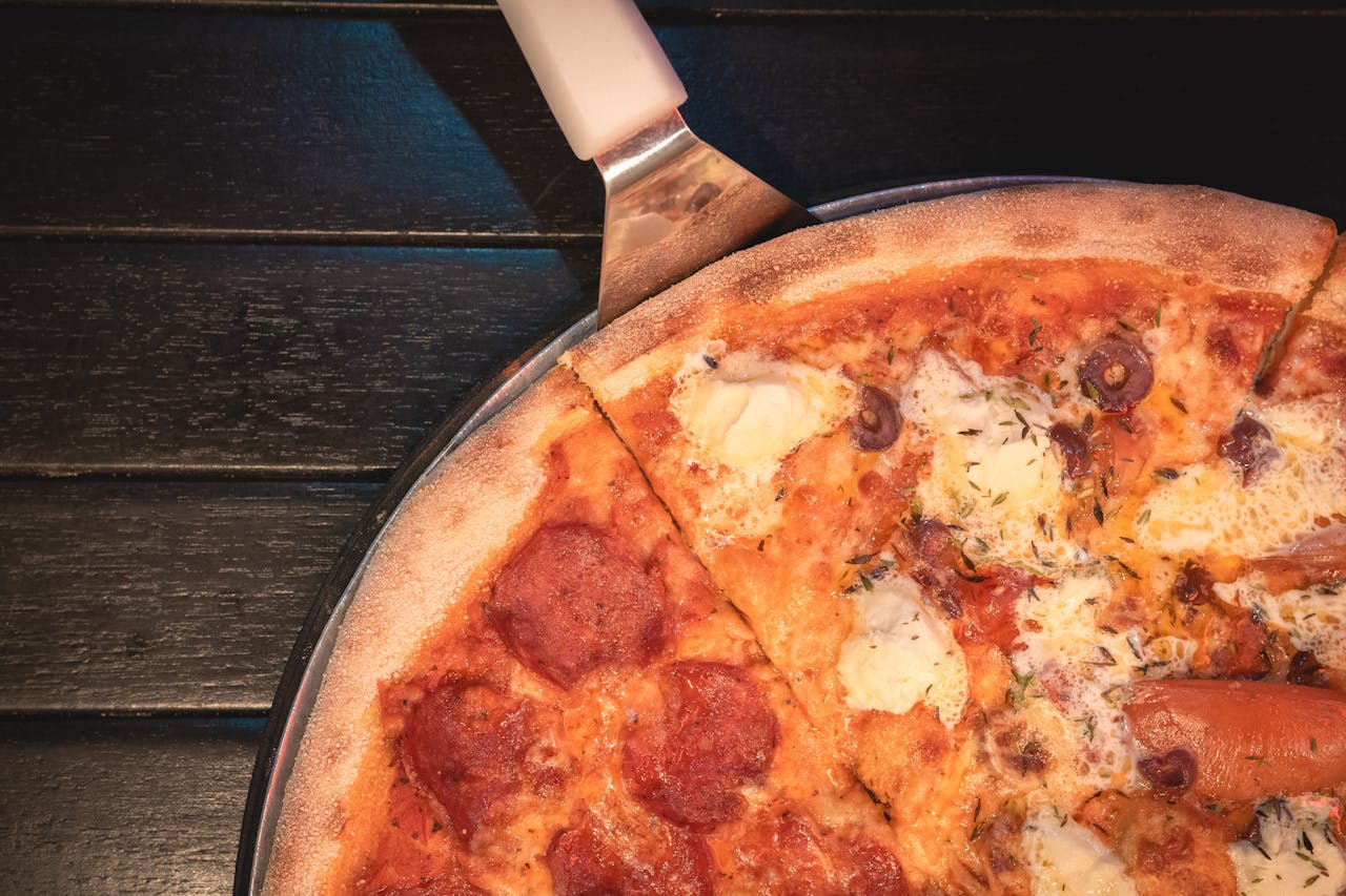 A delicious pepperoni and cheese pizza with herbs, captured from above on a dark wooden table.