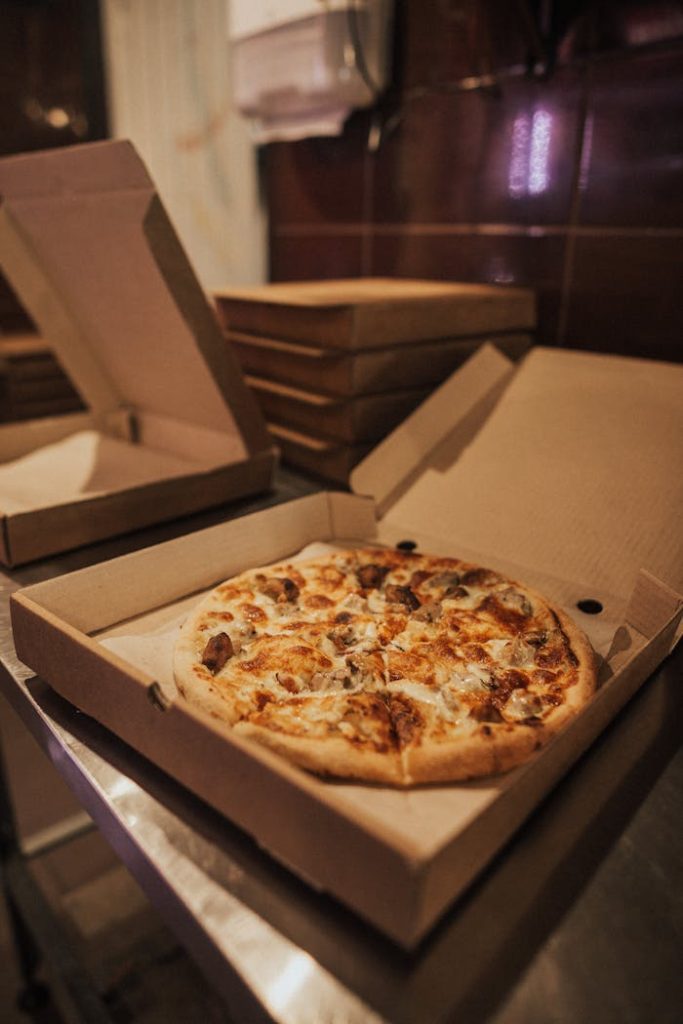 pexels photo 5056617 Delicious hot pizza with toppings in an open takeout box on a restaurant table.