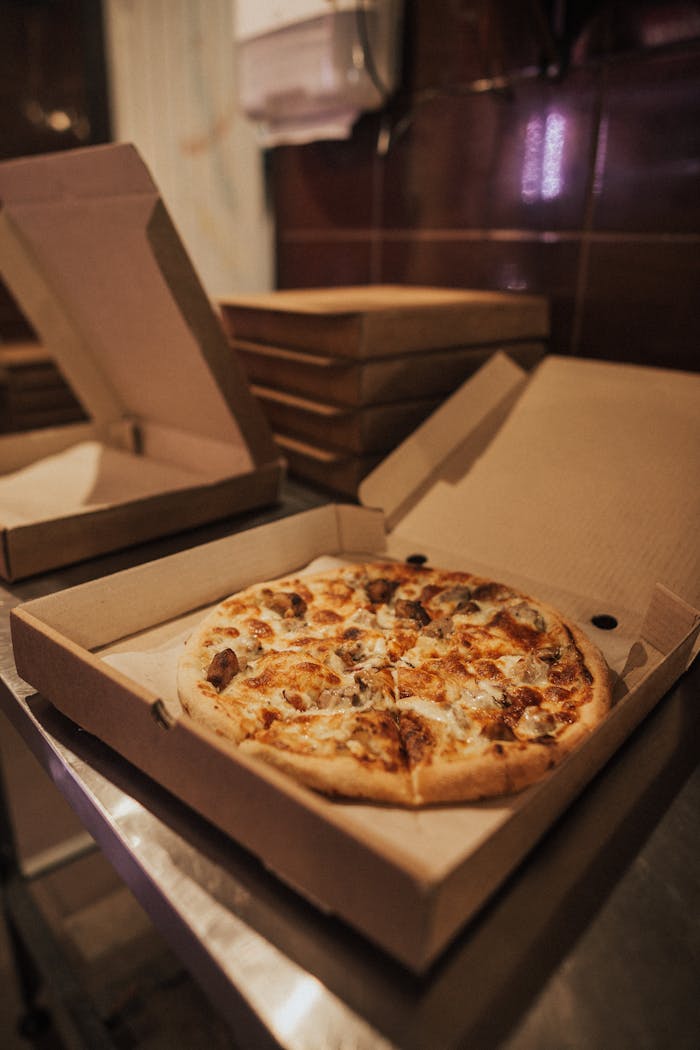 Delicious hot pizza with toppings in an open takeout box on a restaurant table.