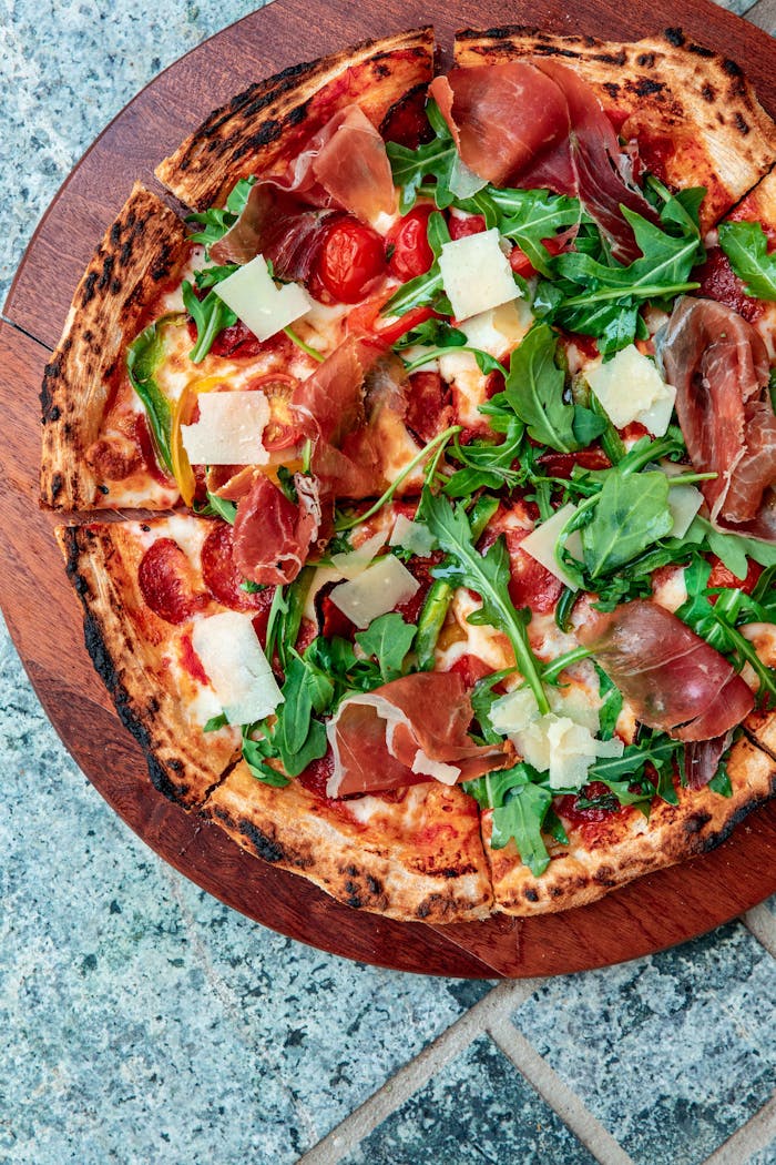 Delicious pizza topped with arugula, prosciutto, and parmesan on a rustic wooden board.